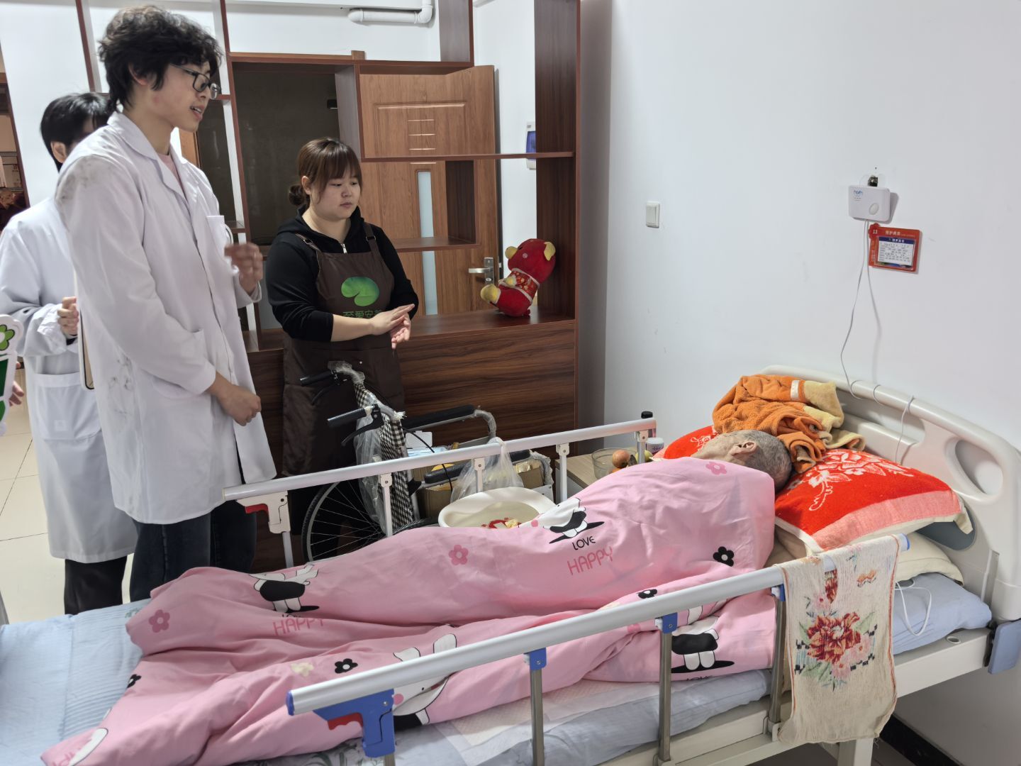 Volunteers speaking with a caregiver beside a resident