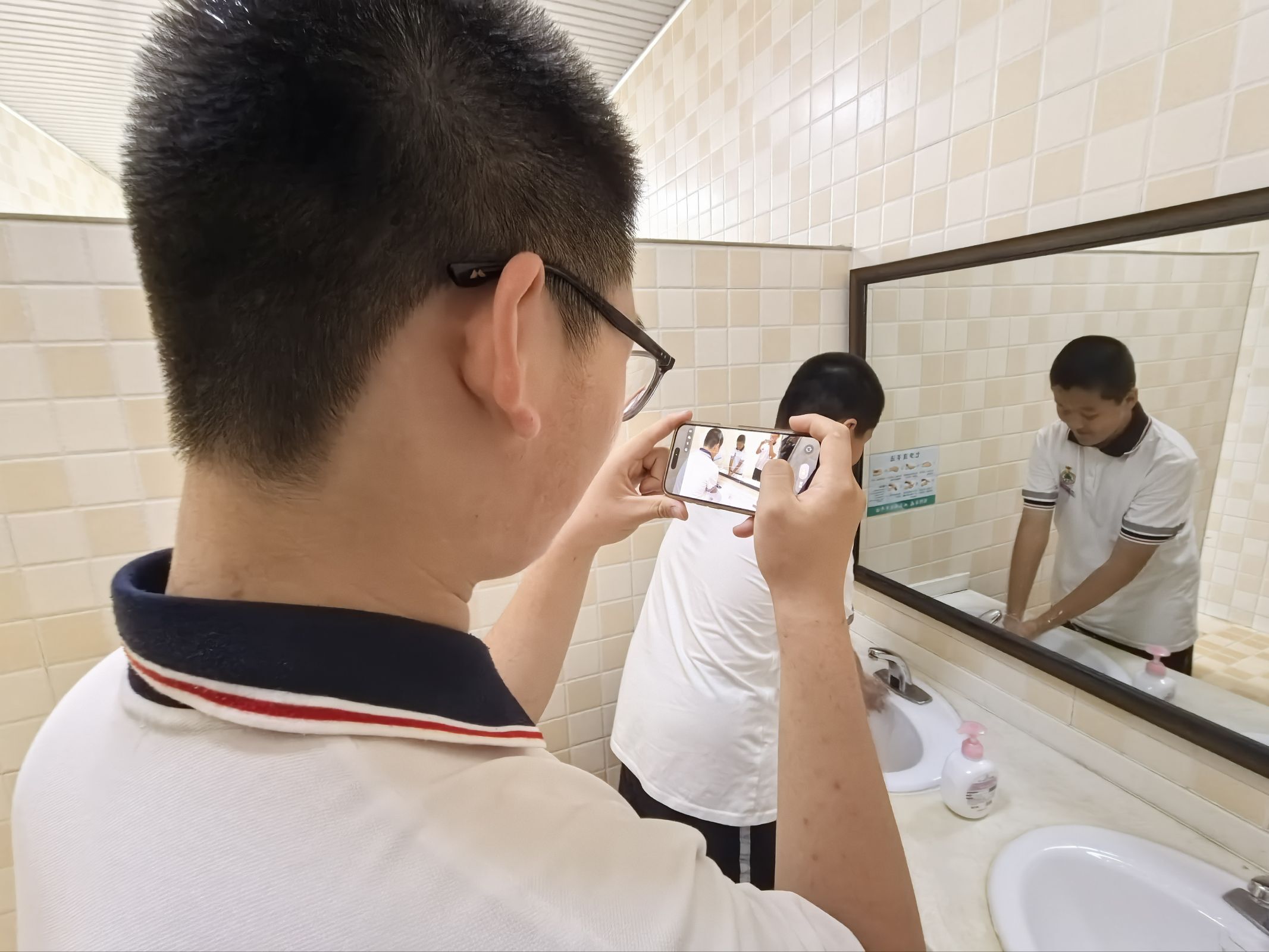 A student filming a handwashing scene at the sinks