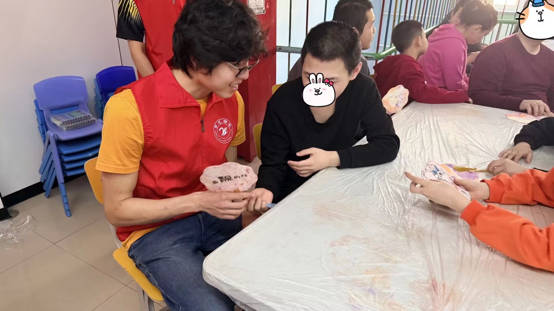 A volunteer supporting a participant during a table activity