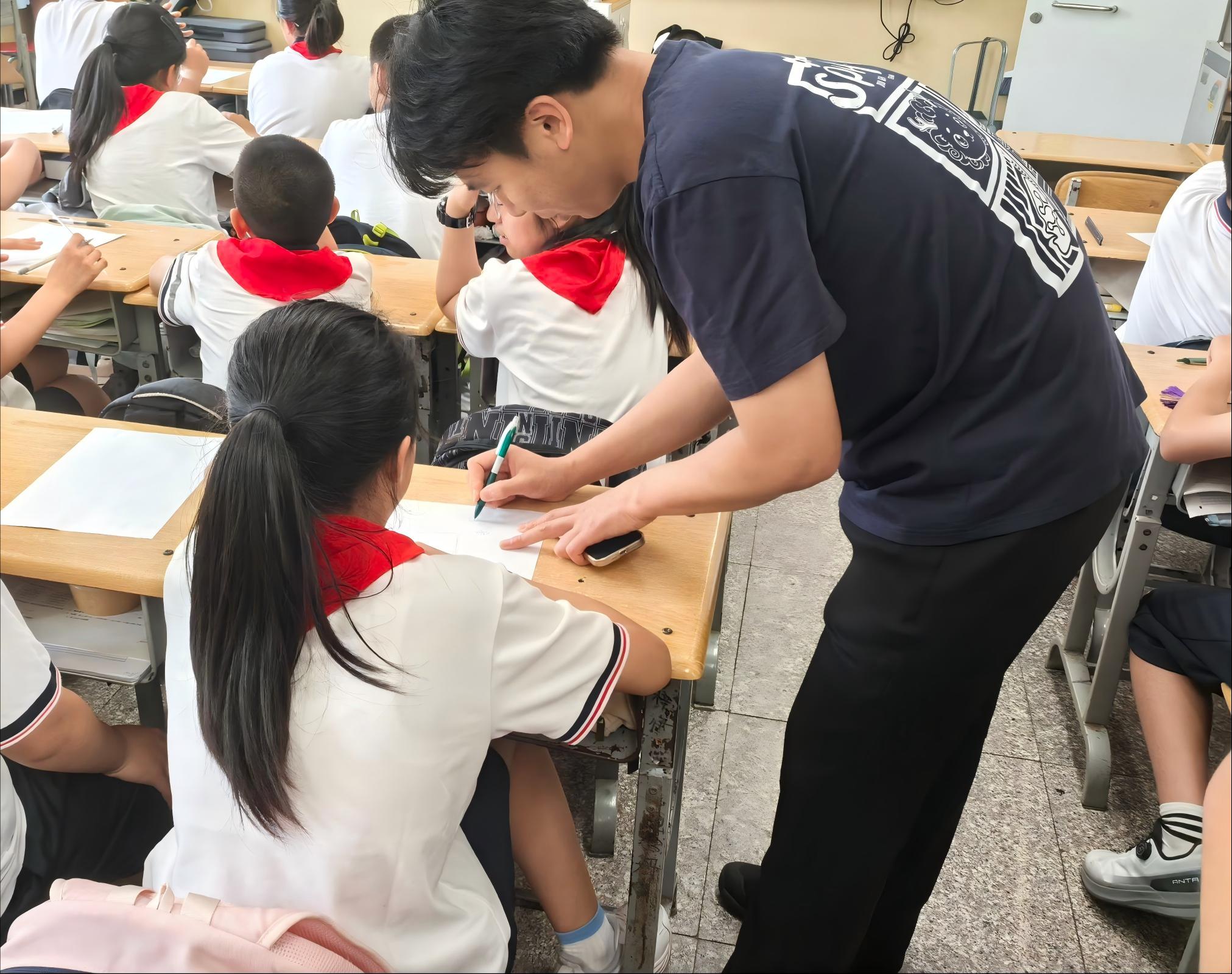 A volunteer discussing a student design at a desk