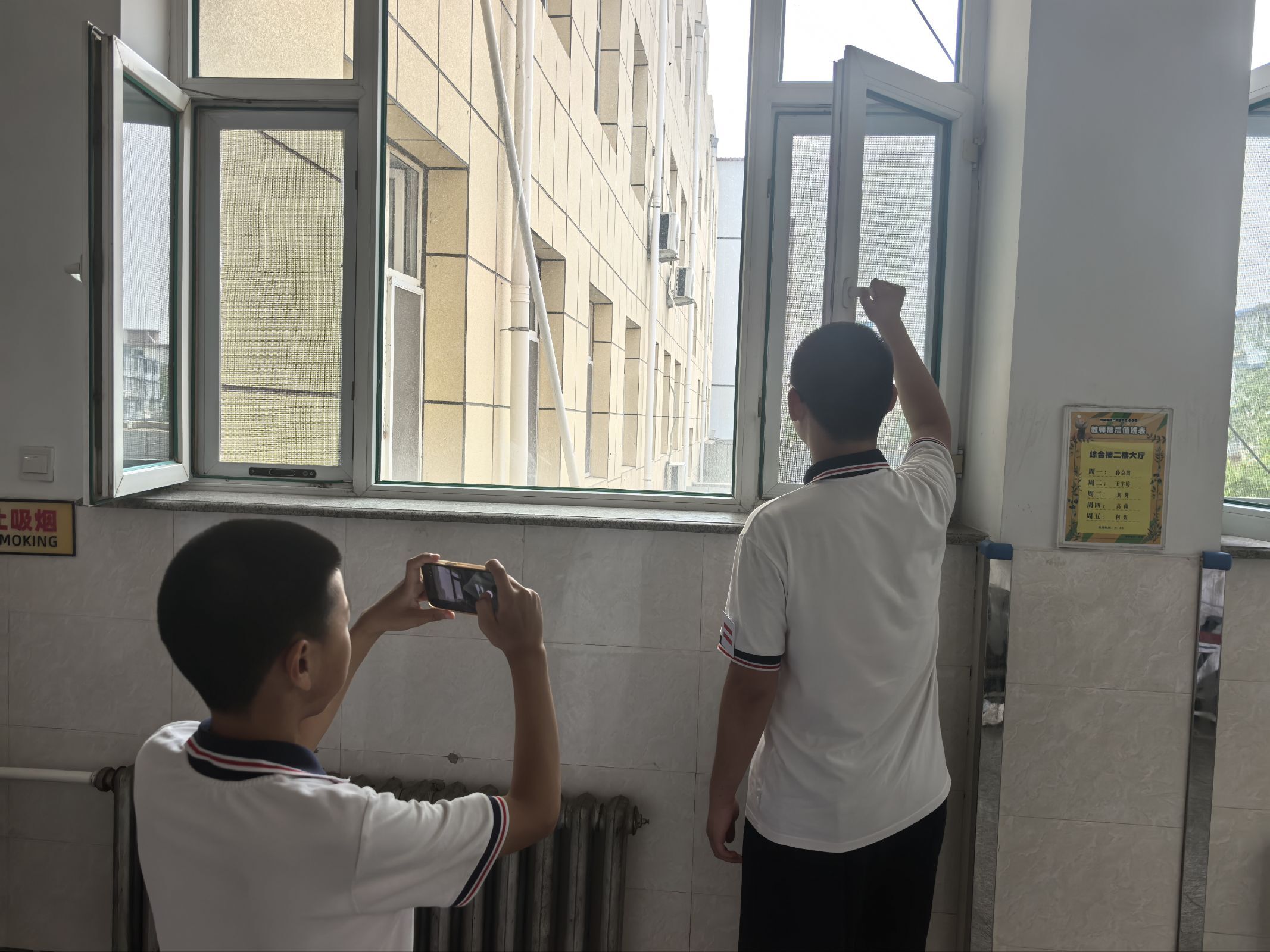 A student filming a classmate near a classroom window