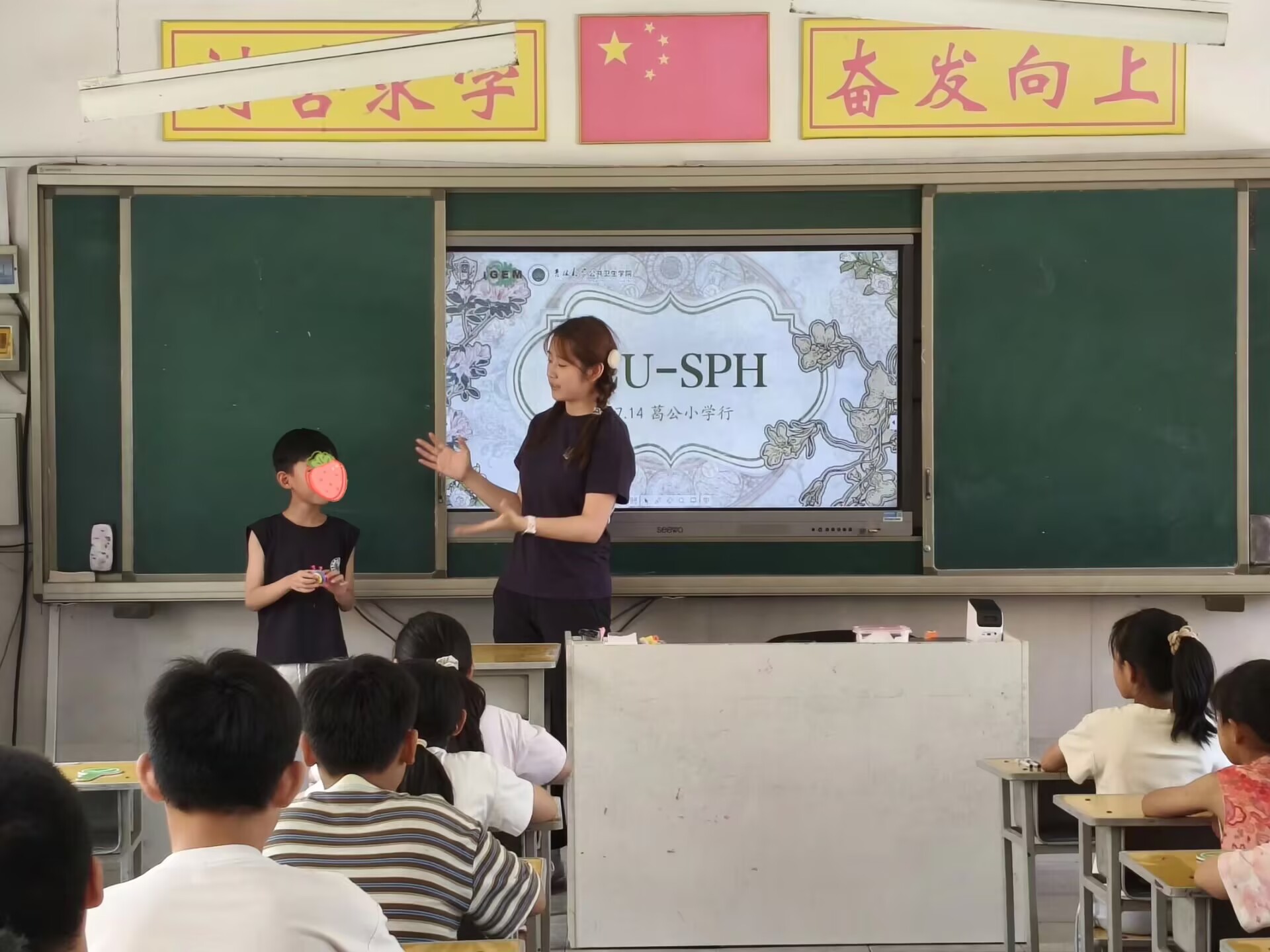 A student joining the presenter at the front of the classroom